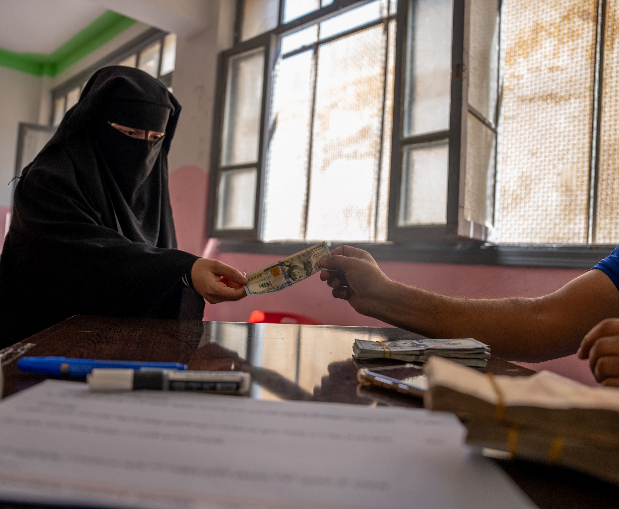 Syrian woman in black veil receiving cash for necessities like food