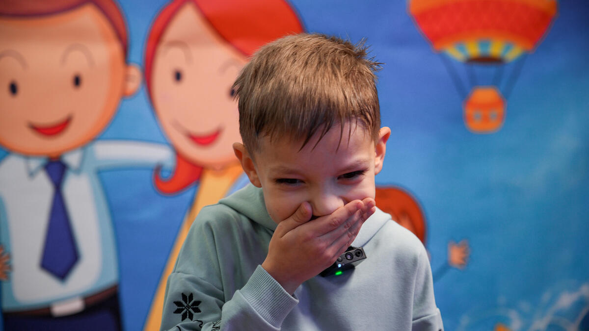 Boy laughing with his hand over his mouth