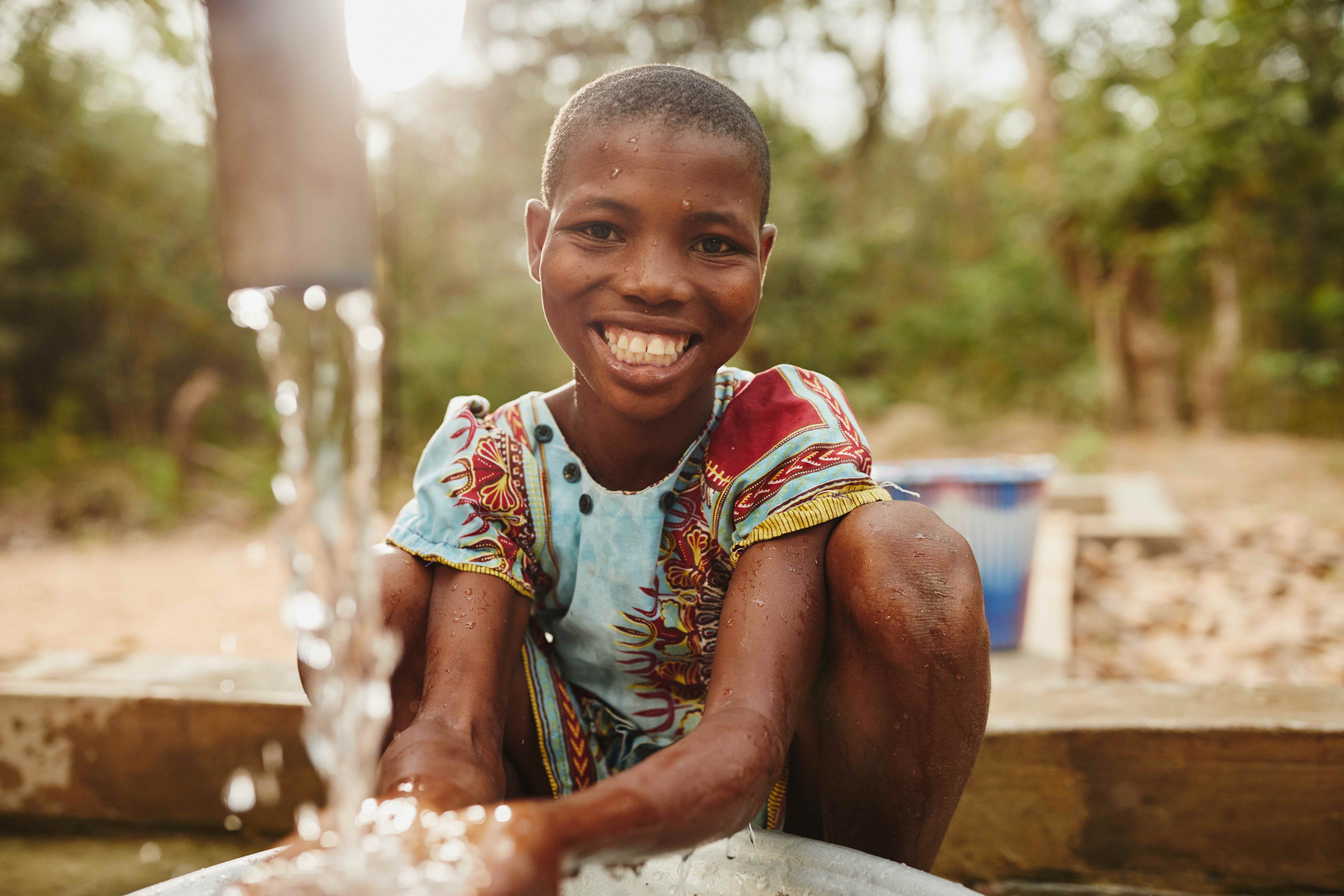 Young girl smiles as water pours from tap