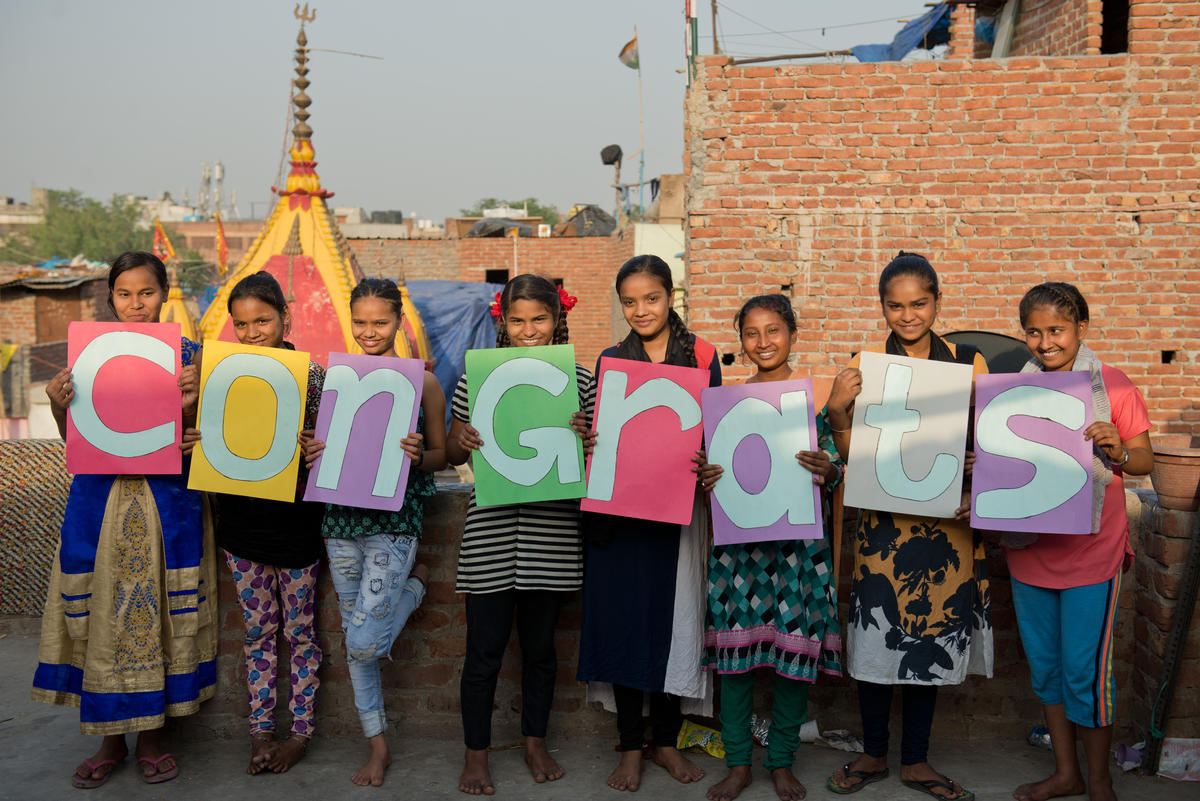 Young girls in India hold letters reading 'congrats' for Meghan Markle