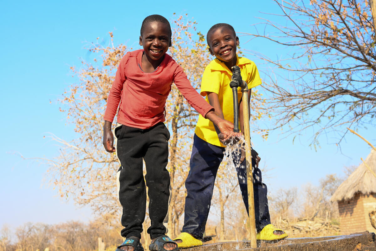 Two boys using a water pump in Zambia