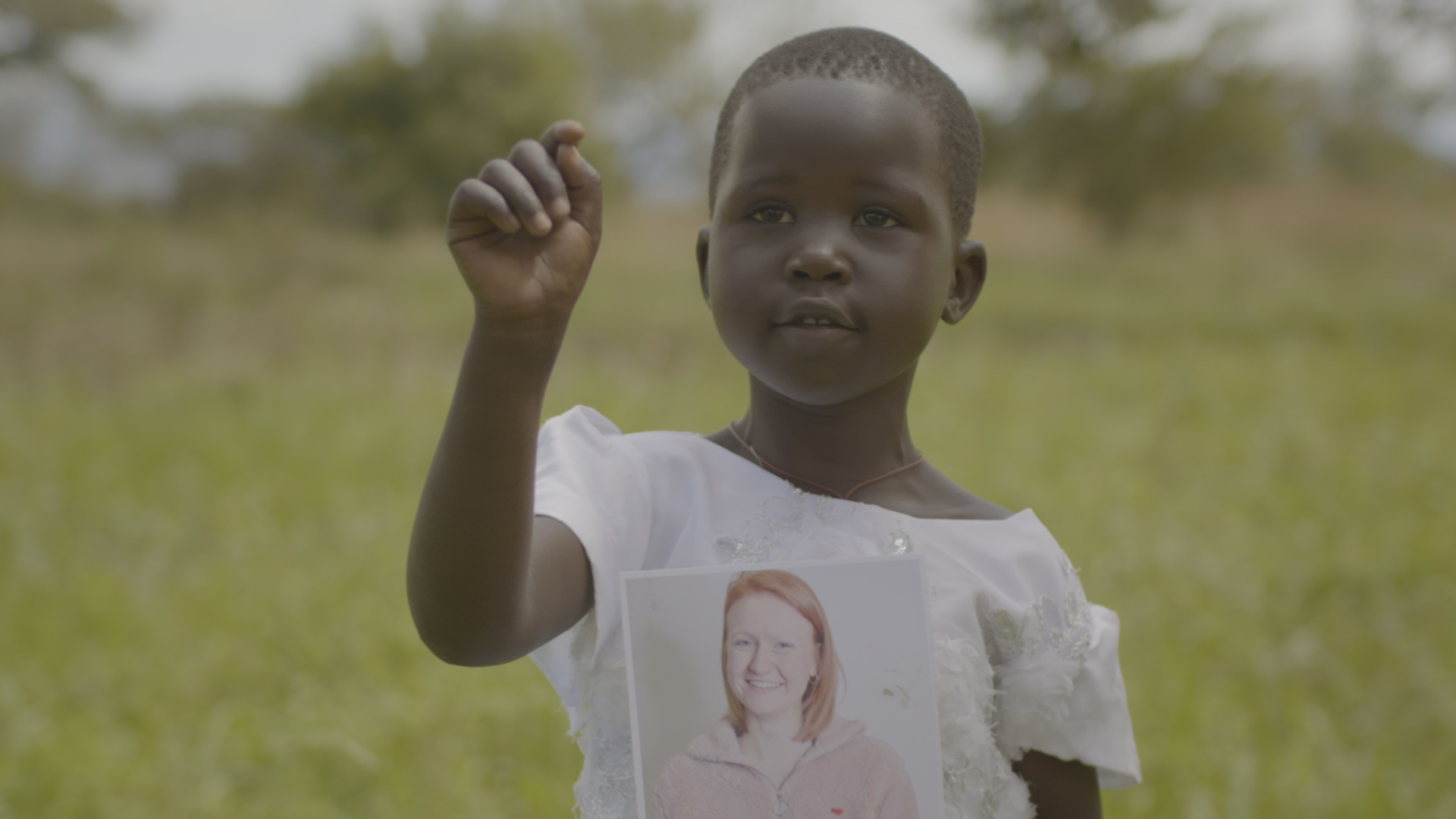 Child holds a photo of the sponsor she chose