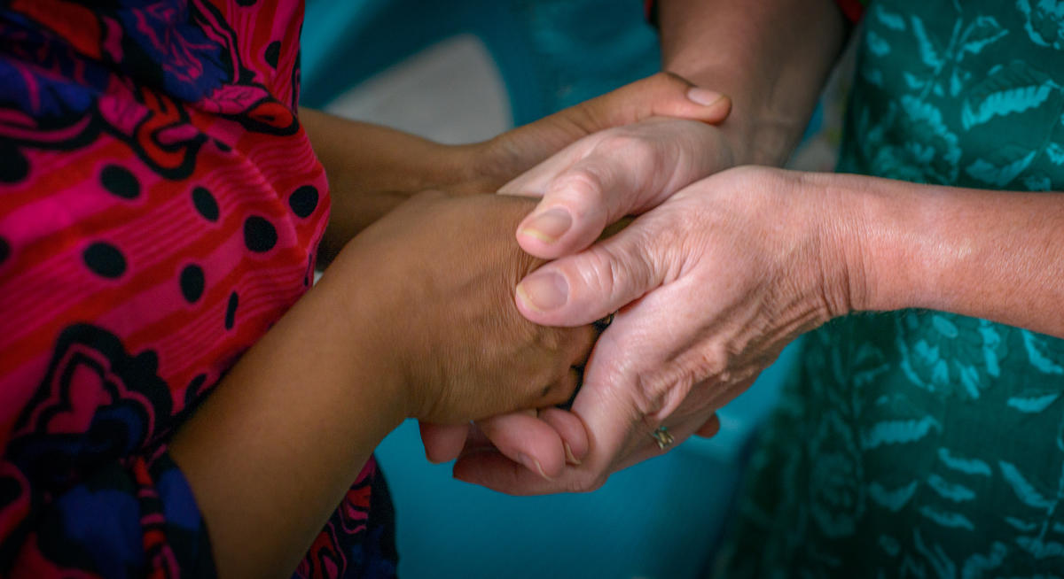 Two pairs of hands clasping each other