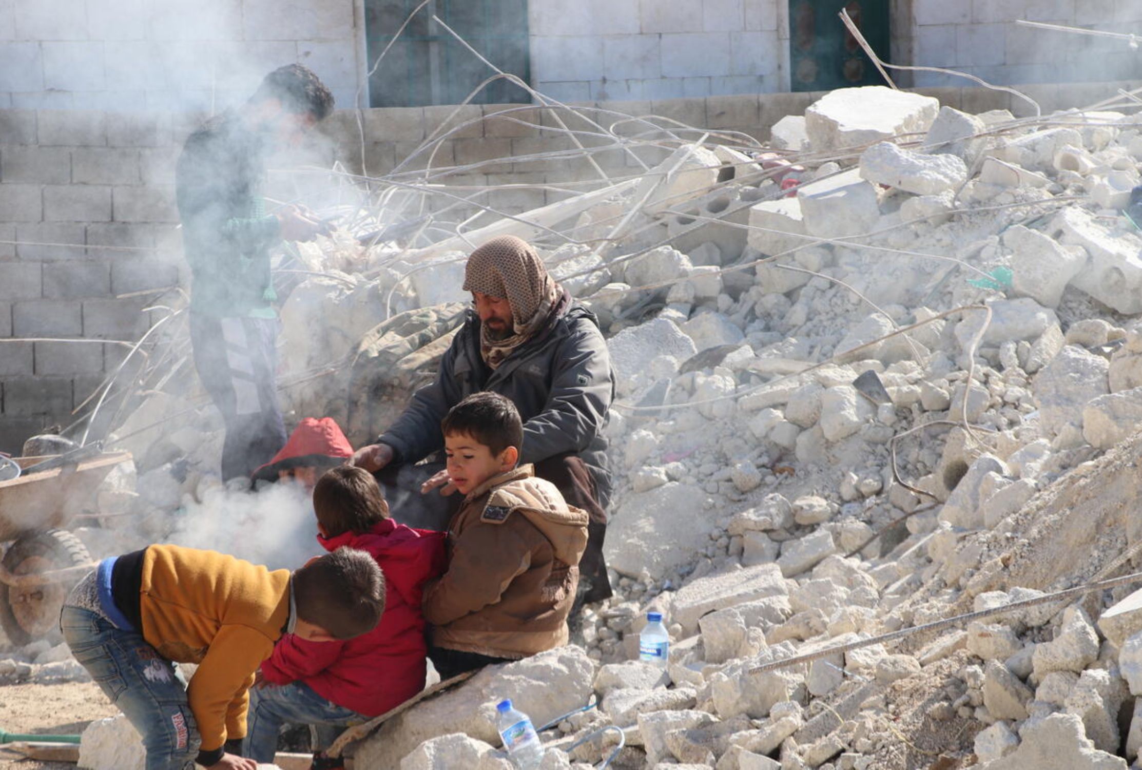 Syrian family surrounded by rubble and wearing coats to keep them warm