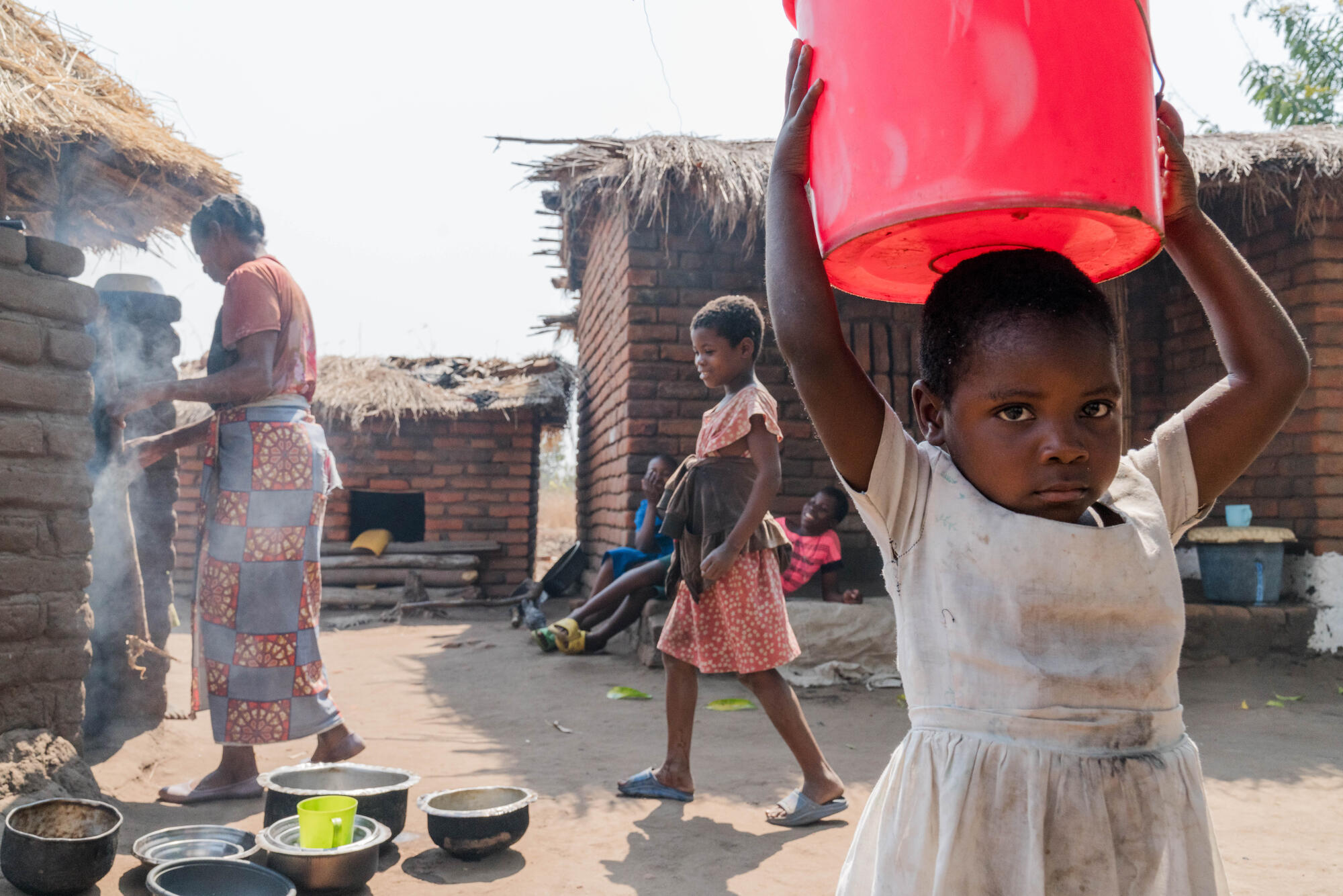 Girl carries bucket of water