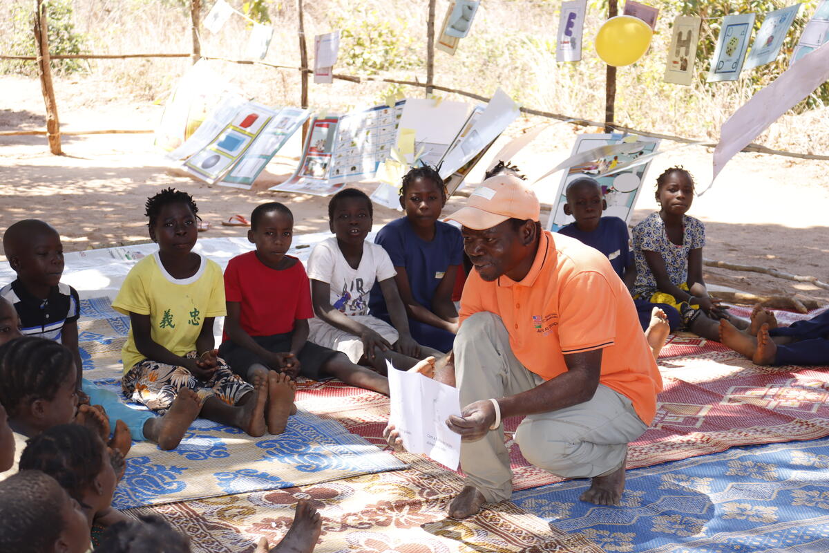 A reading camp promoter helping children with their reading.