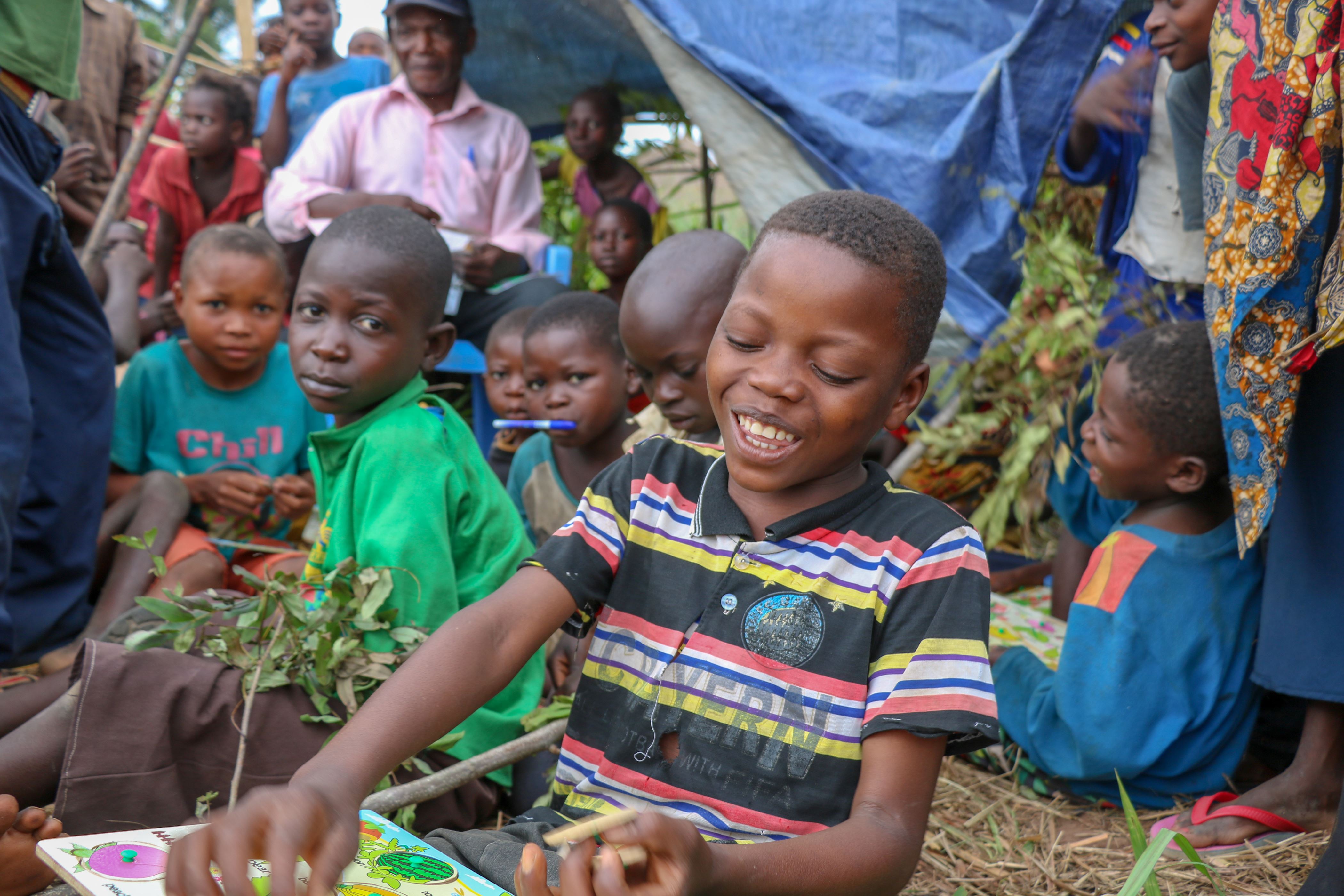 A child, surrounded by others, works on puzzles in one of four Child Friendly Spaces established in Democratic Republic of Congo