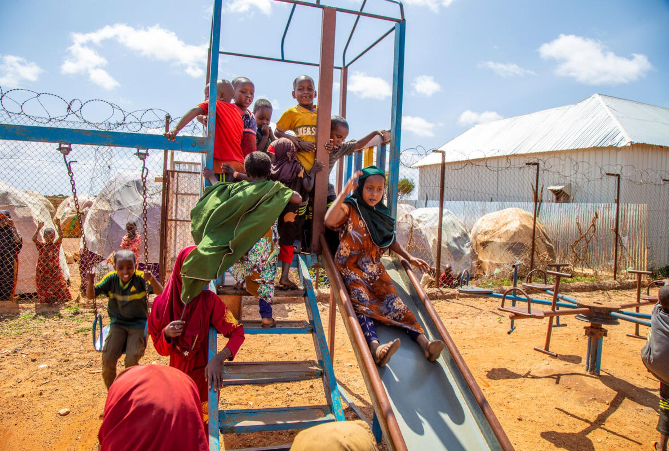 Children playing on swings and a slide at a World Vision Child Friendly Space in Somalia