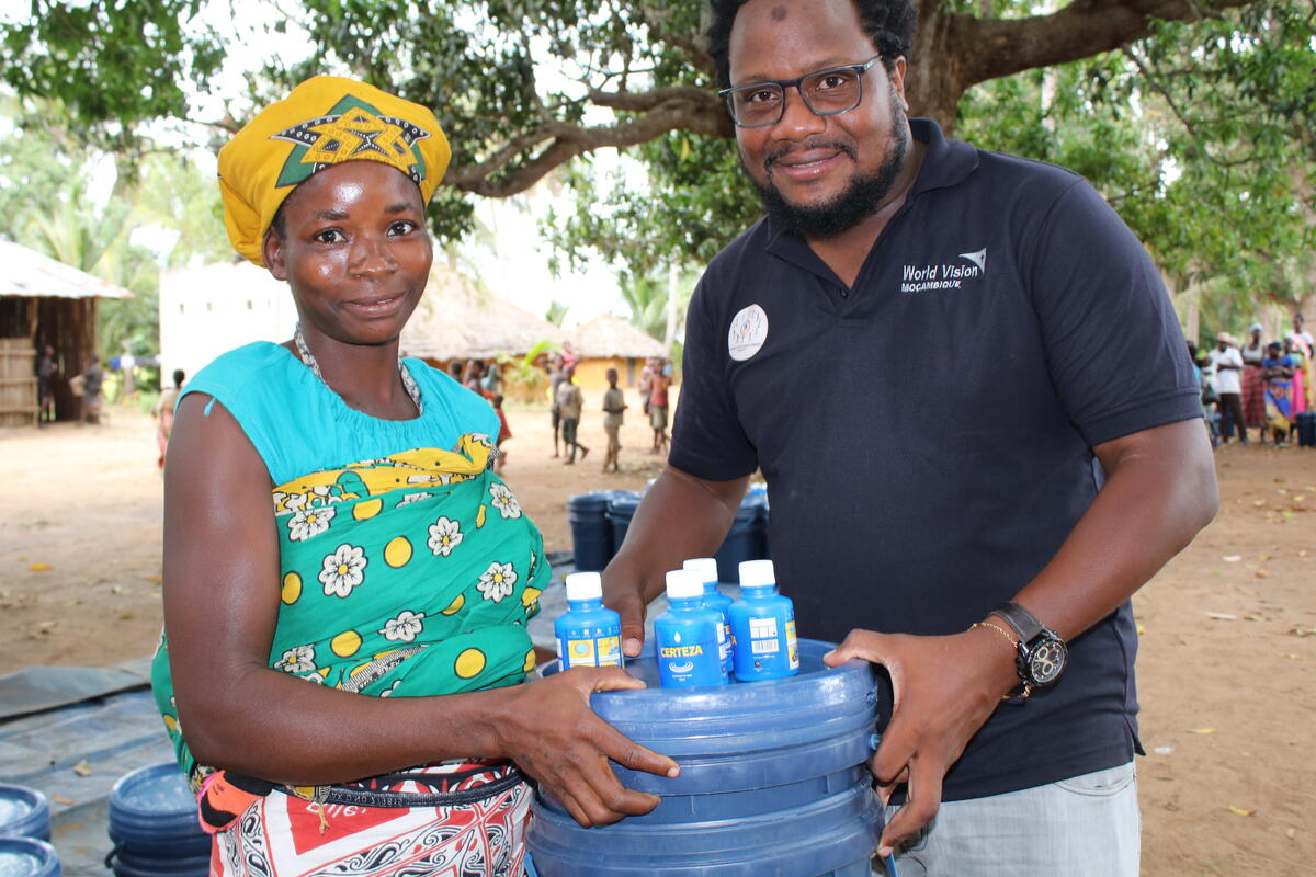 Mother from Malawi holding a water container with a World Vision staff member