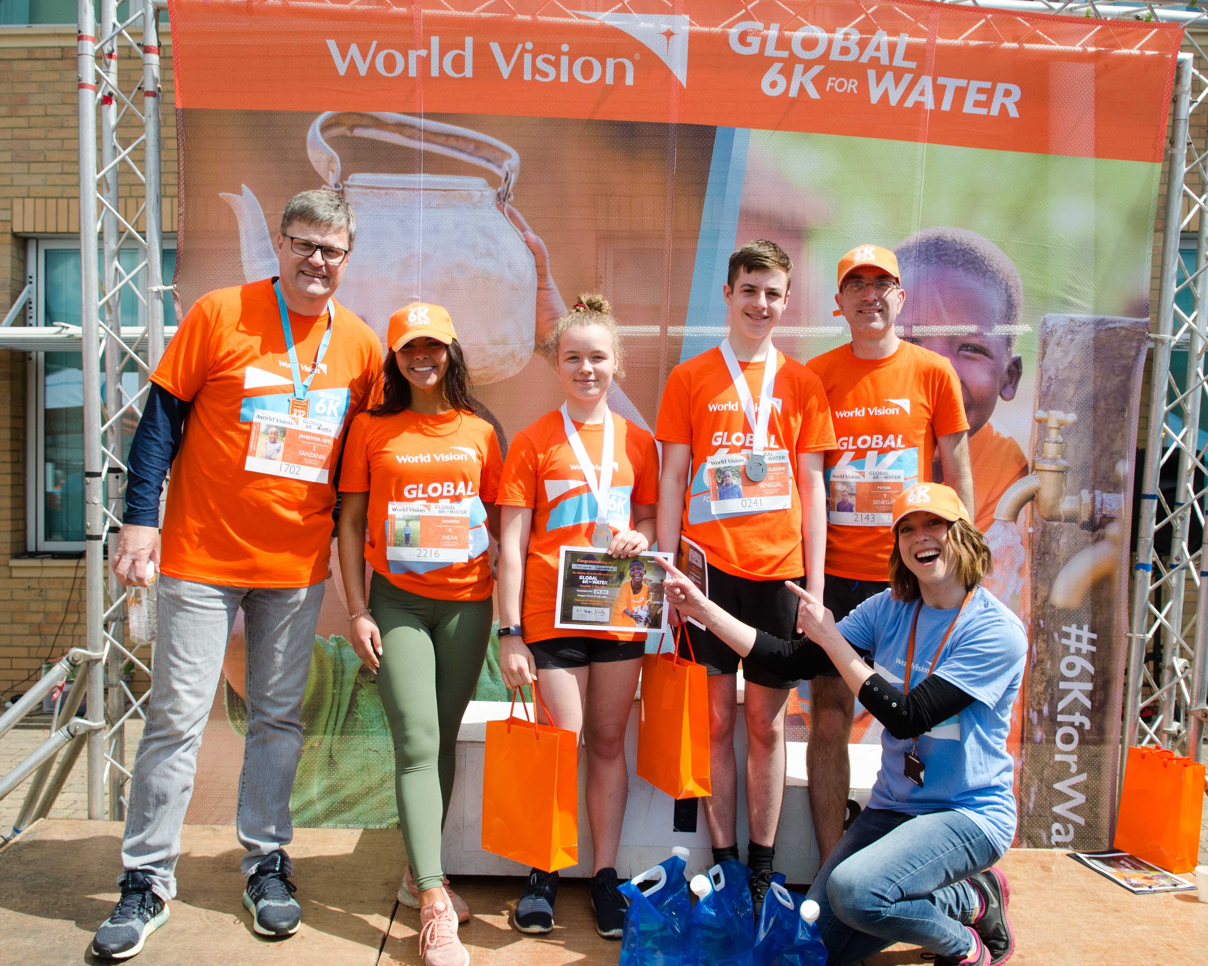 Group stand on podium after finishing race, smiling