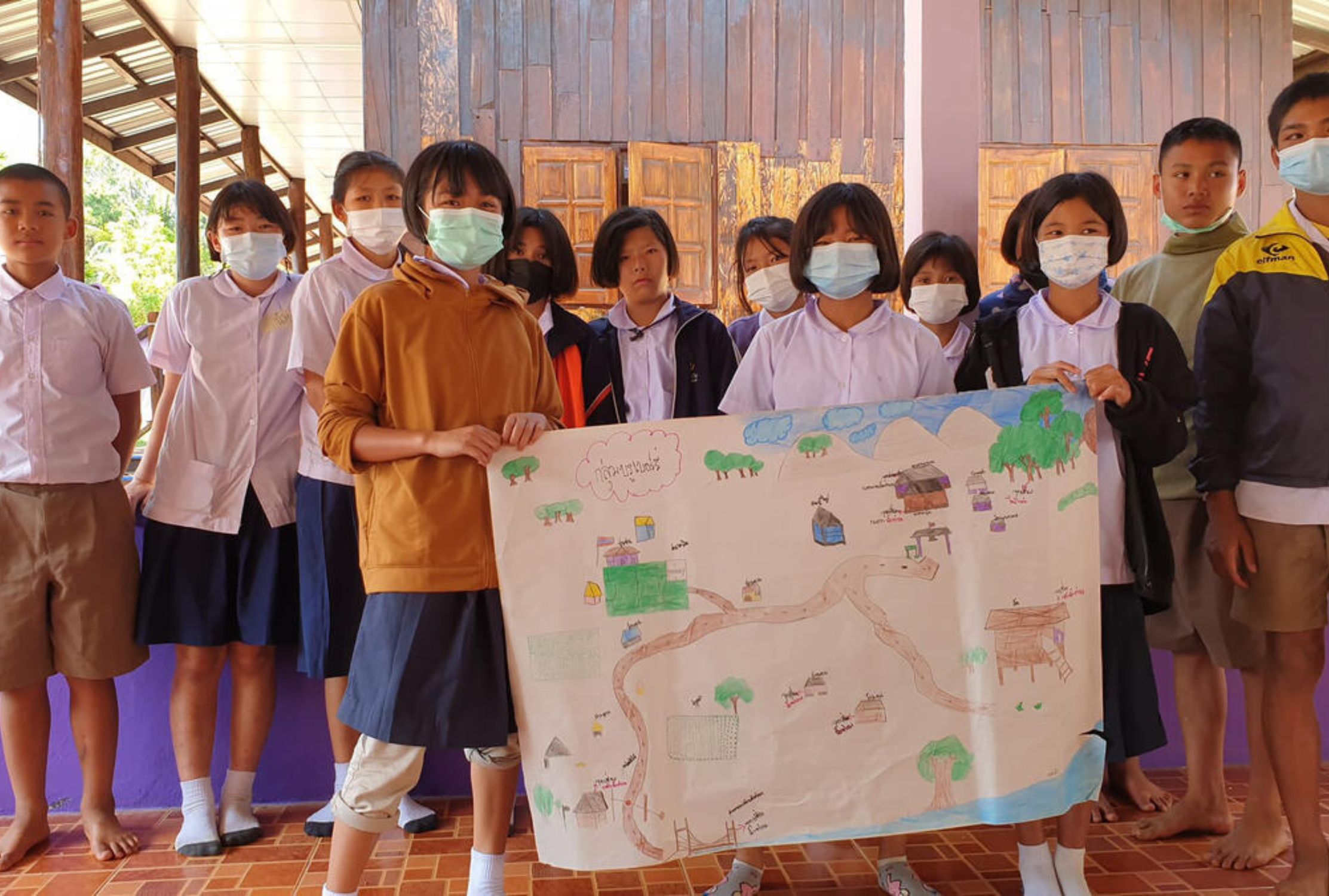 Thai school children holding up a map of flood risk areas in their village
