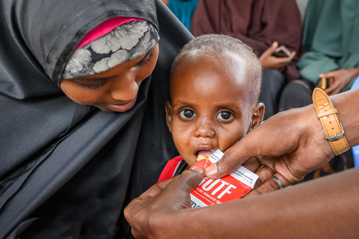 Young toddler is fed with a food pack
