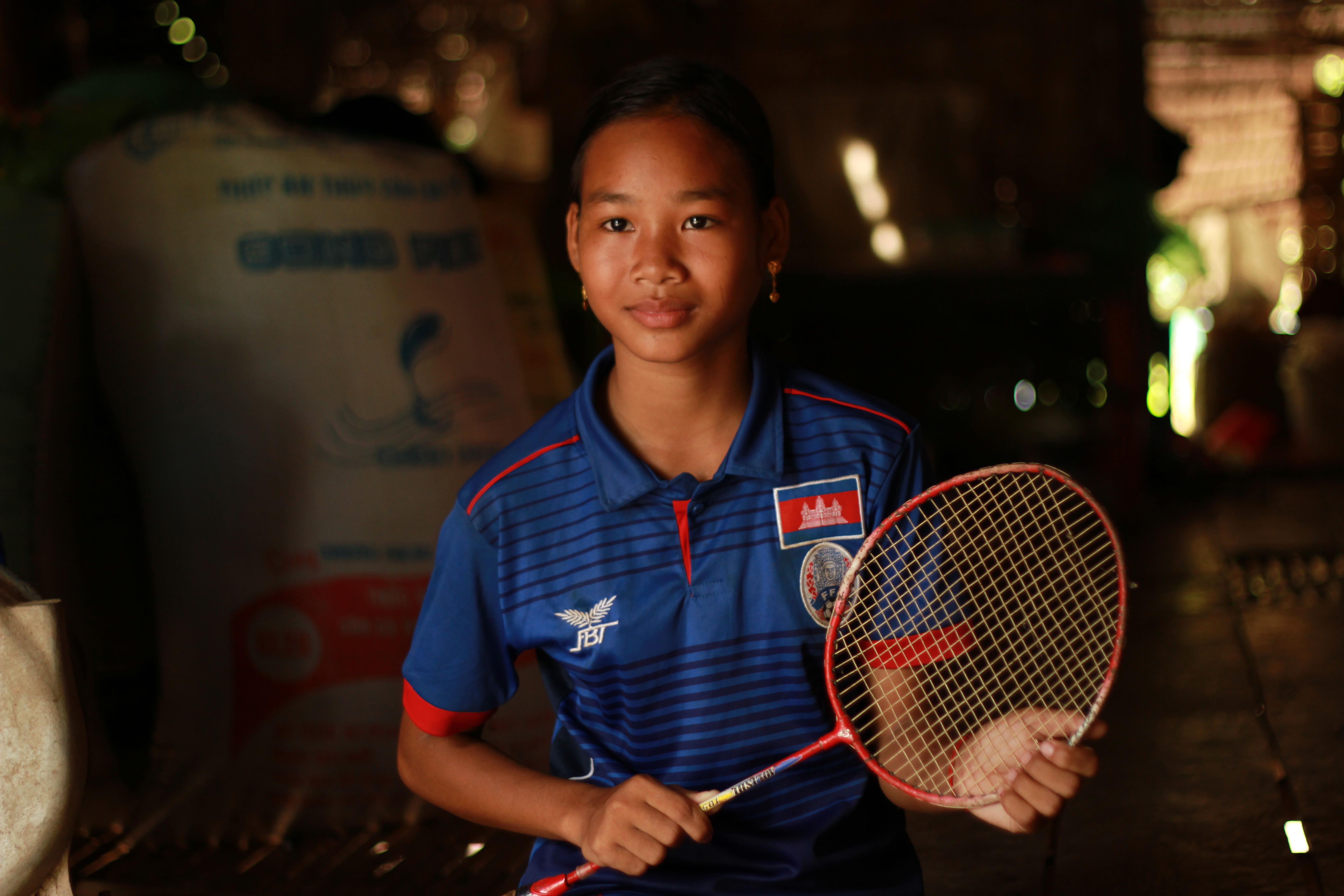 A girl smiles and holds her new tennis racquet