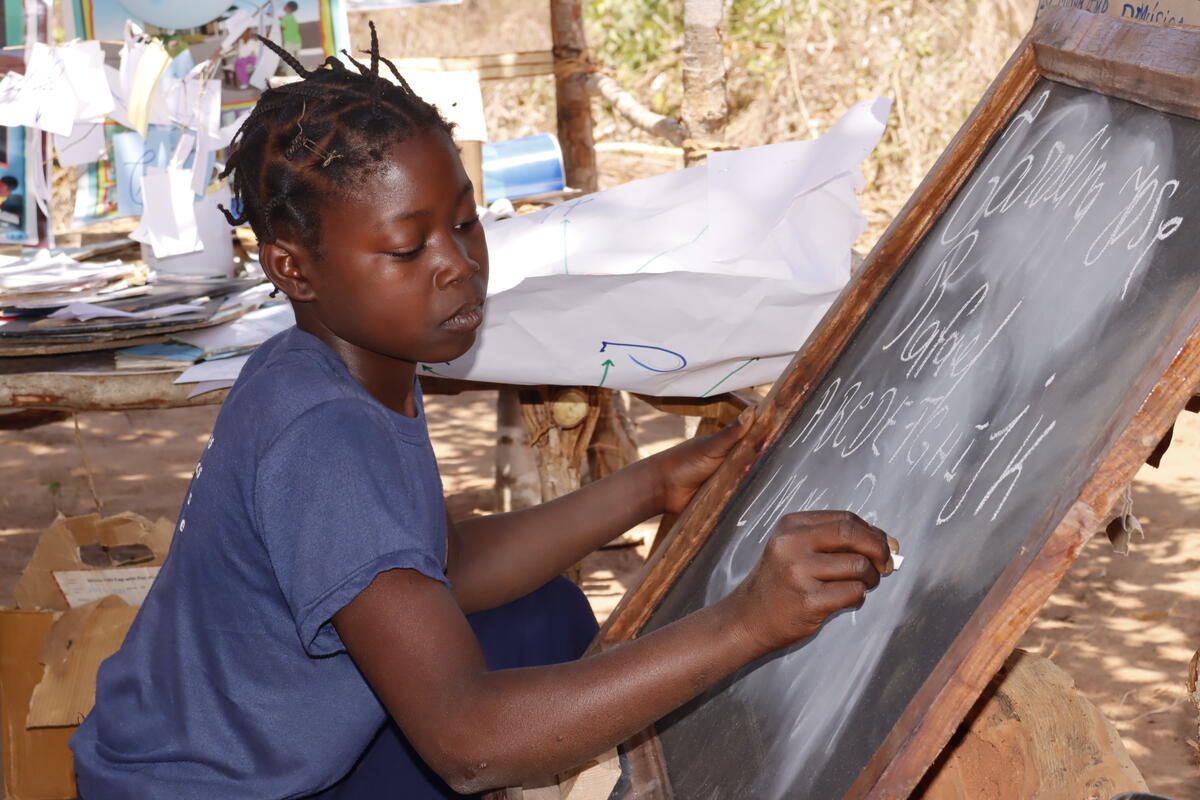 A girl writing on a blackboard at a reading camp.