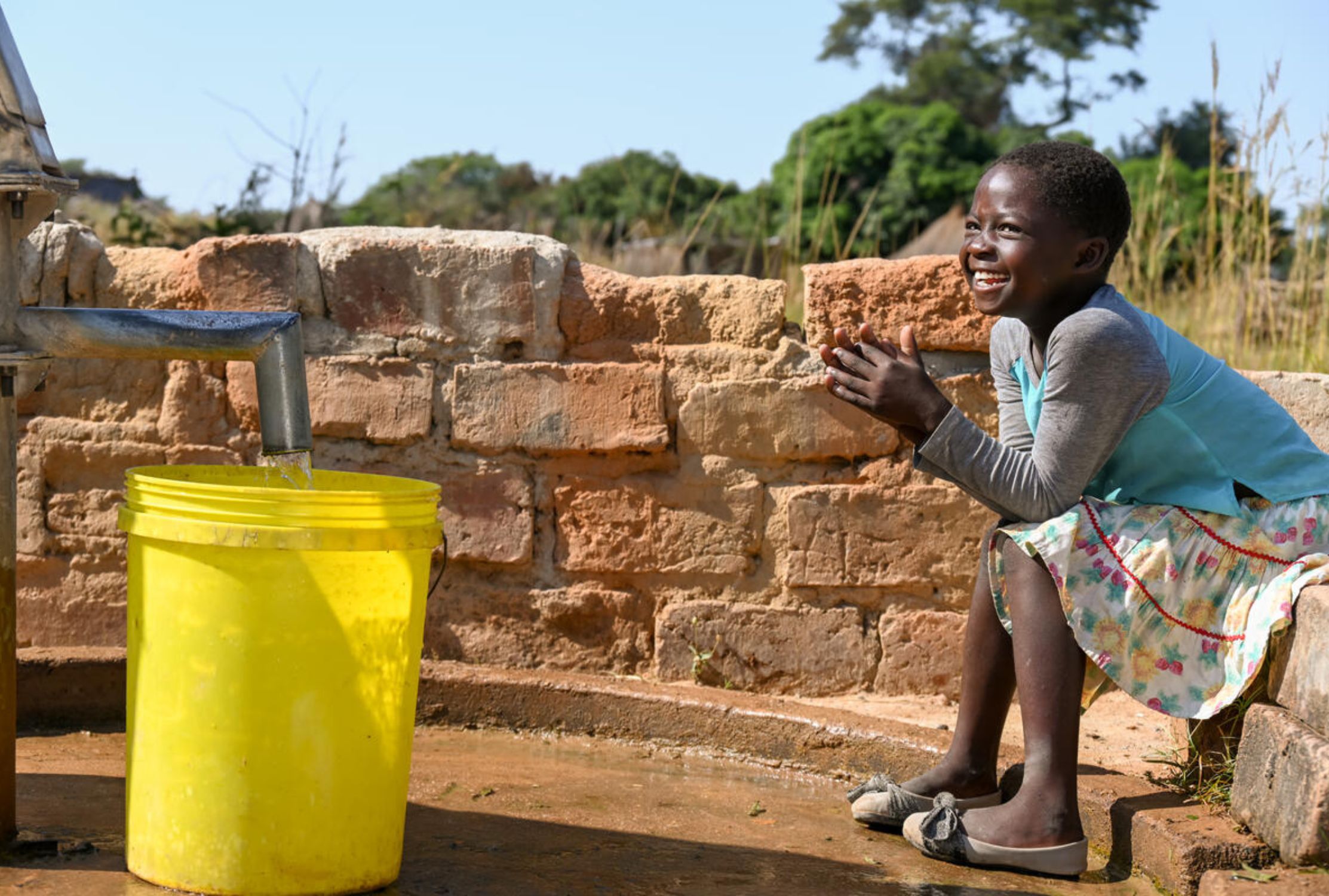 Eight year old girl in Zambia collecting water from a hand pump installed by World Vision