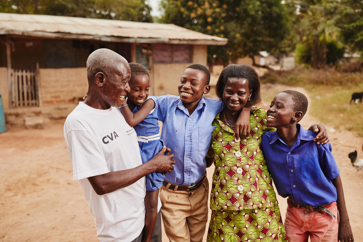 A family of five from Ghana in a row with their arms around each other's shoulders and smiling
