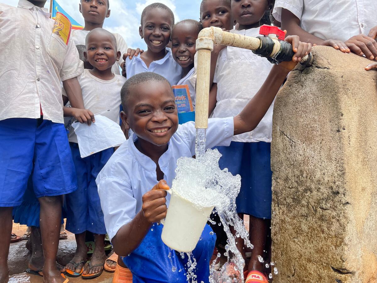 Young boy, Lepetit in DRC, next to a new water tap installed by World Vision in his school. to drink