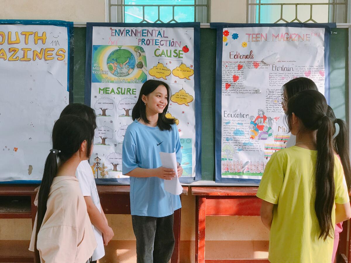 Vietnamese teenage girl holding school paperwork and smiling at her peers