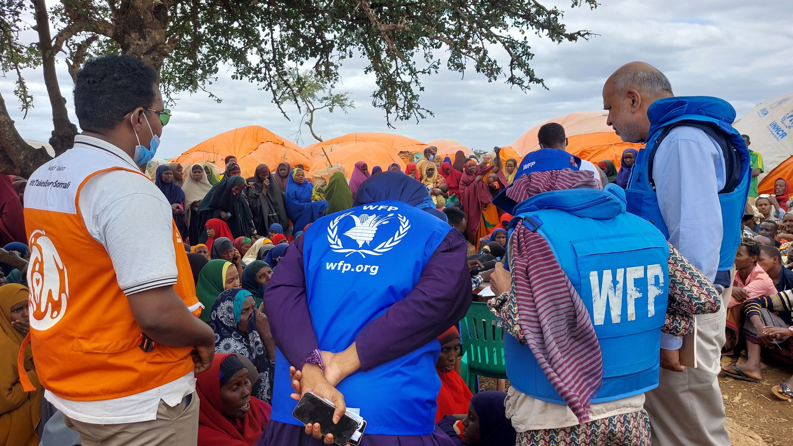 World Vision staff stands shoulder to shoulder with other partners, face away from camera