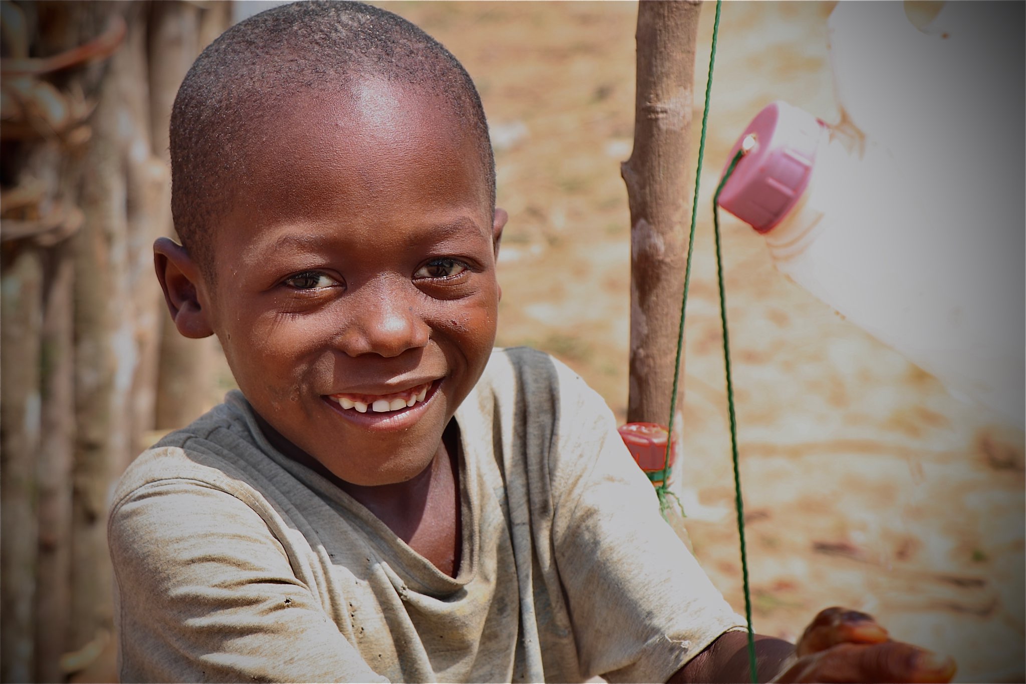 Child from Sierra Leone smiles as they hold their hands up to wash them
