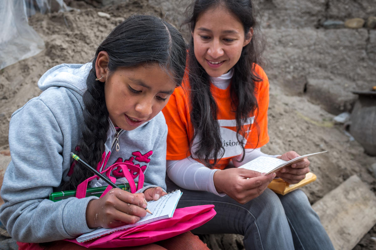 Sponsored child in Bolivia writes a letter as her friend sits next to her