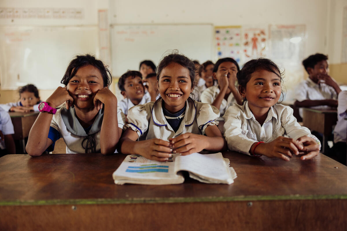 School children sitting at a desk and smiling