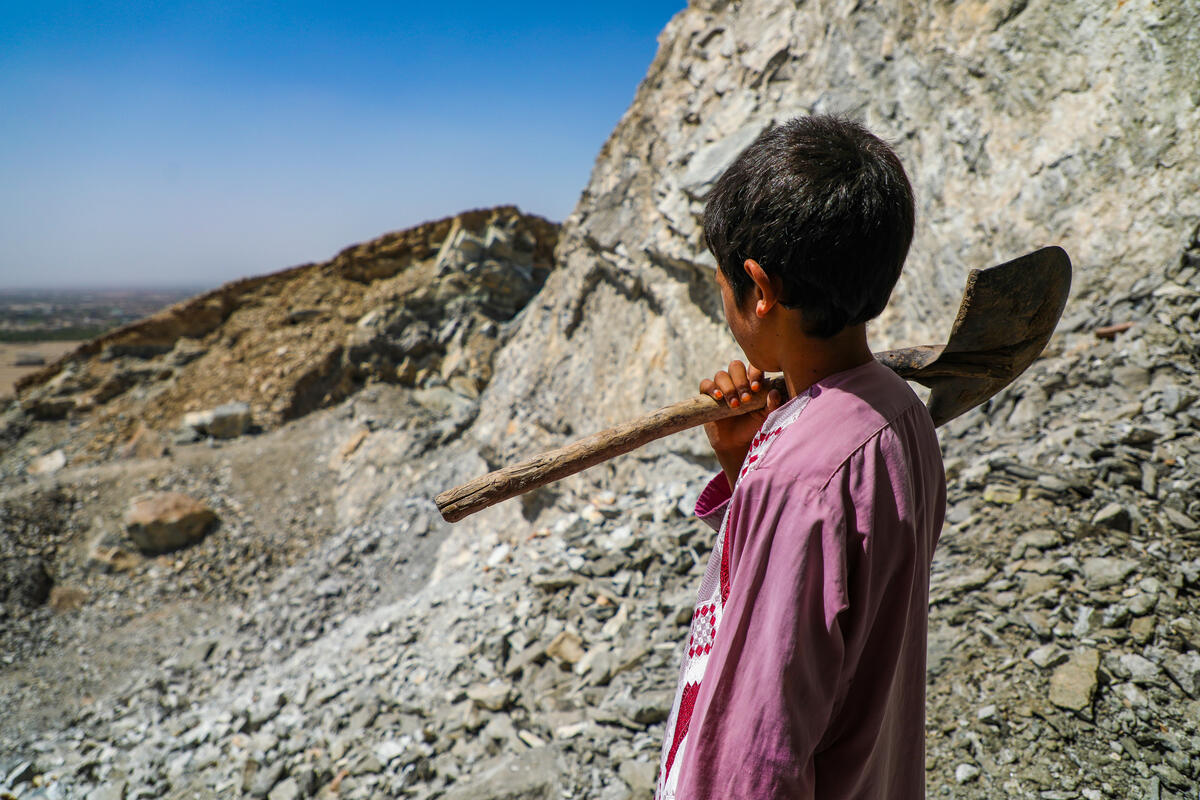 An Afghan boy holding a shovel.
