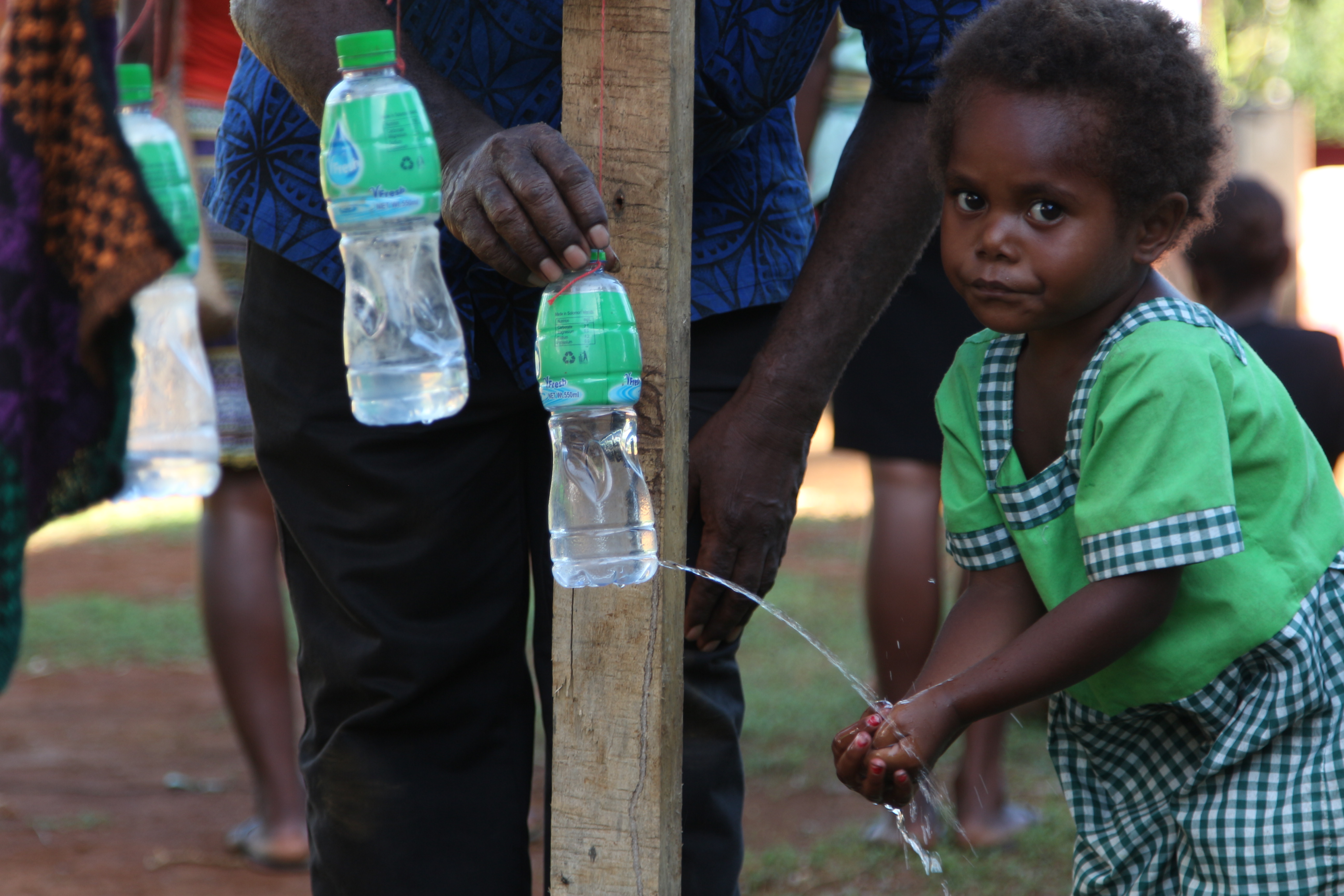 Little girl Fragrance uses a homemade tippy tap to wash her hands