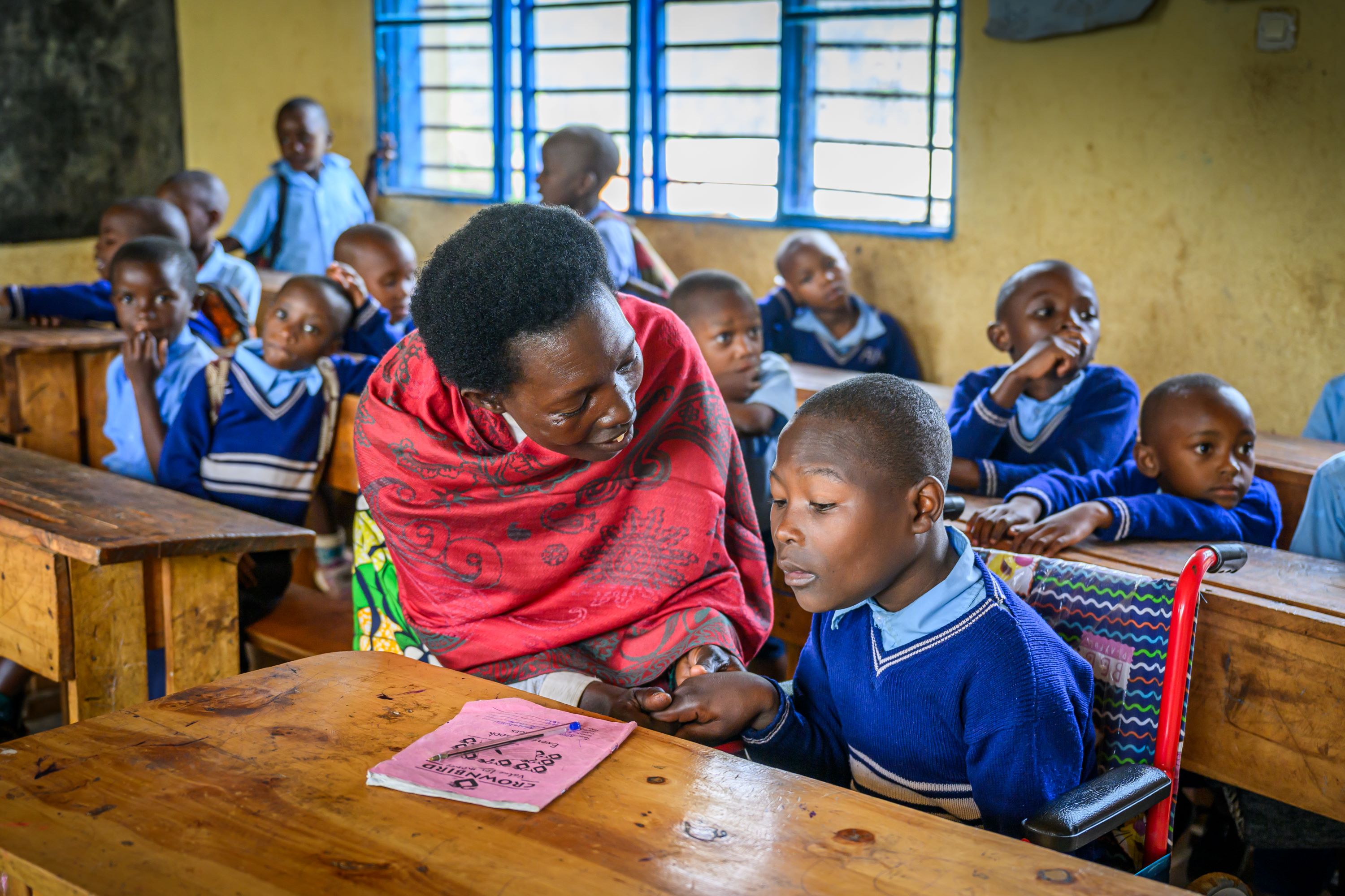 Rwandan schoolboy sitting in wheelchair at his classroom desk