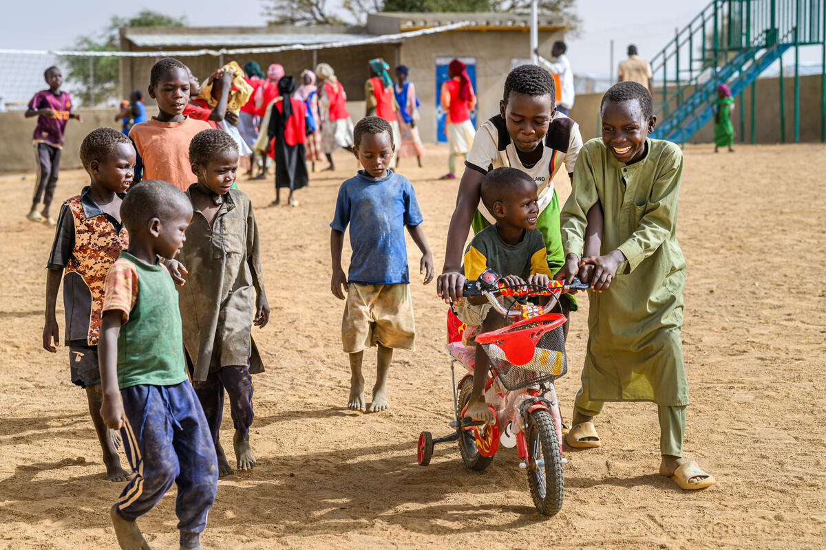 Children from Sudan play with a bicycle in a refugee camp in Chad