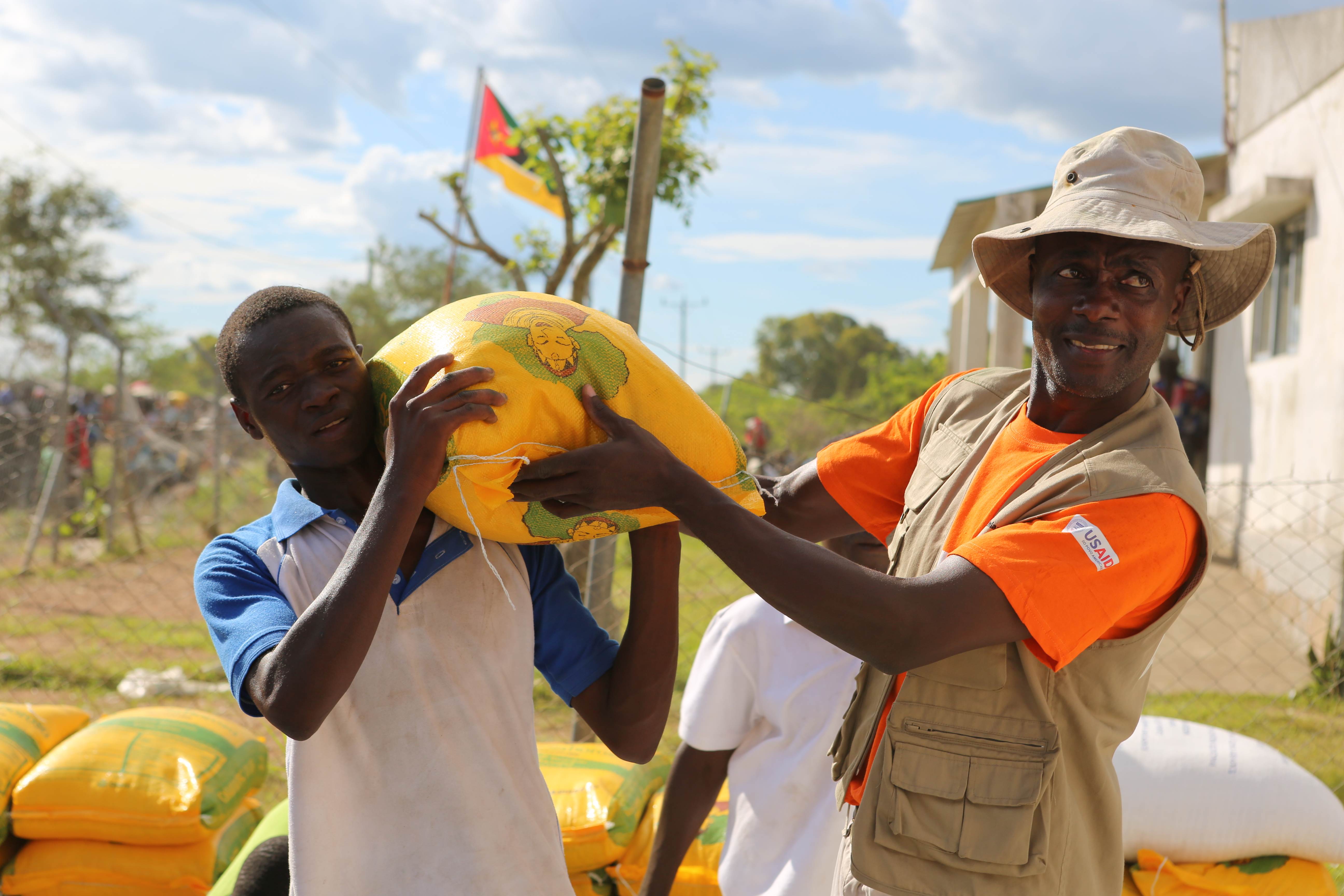 World Vision worker in Mozambique helps another man hold a bag over his shoulder
