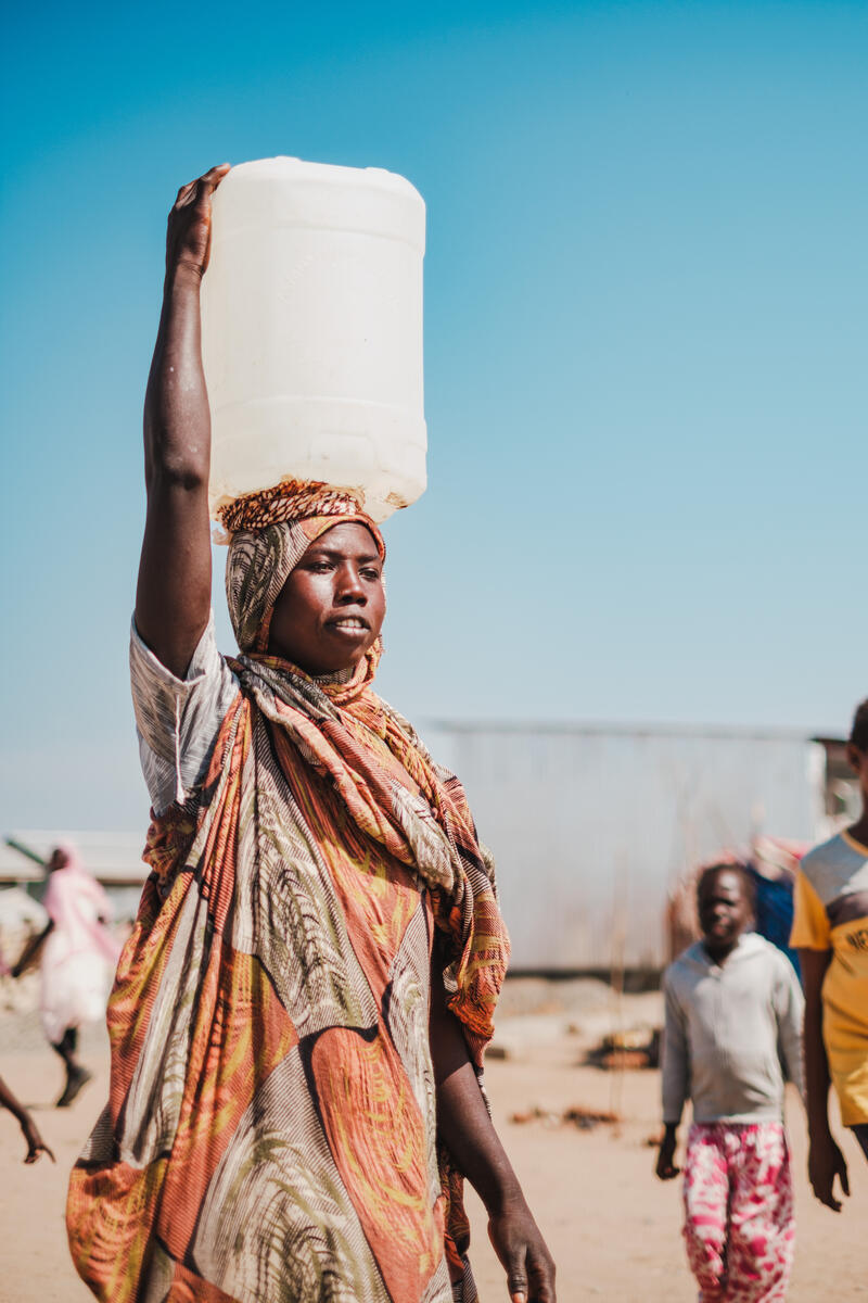 A woman in South Sudan carrying a container of fresh water.