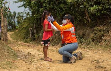 World Vision staff help a child fit their mask