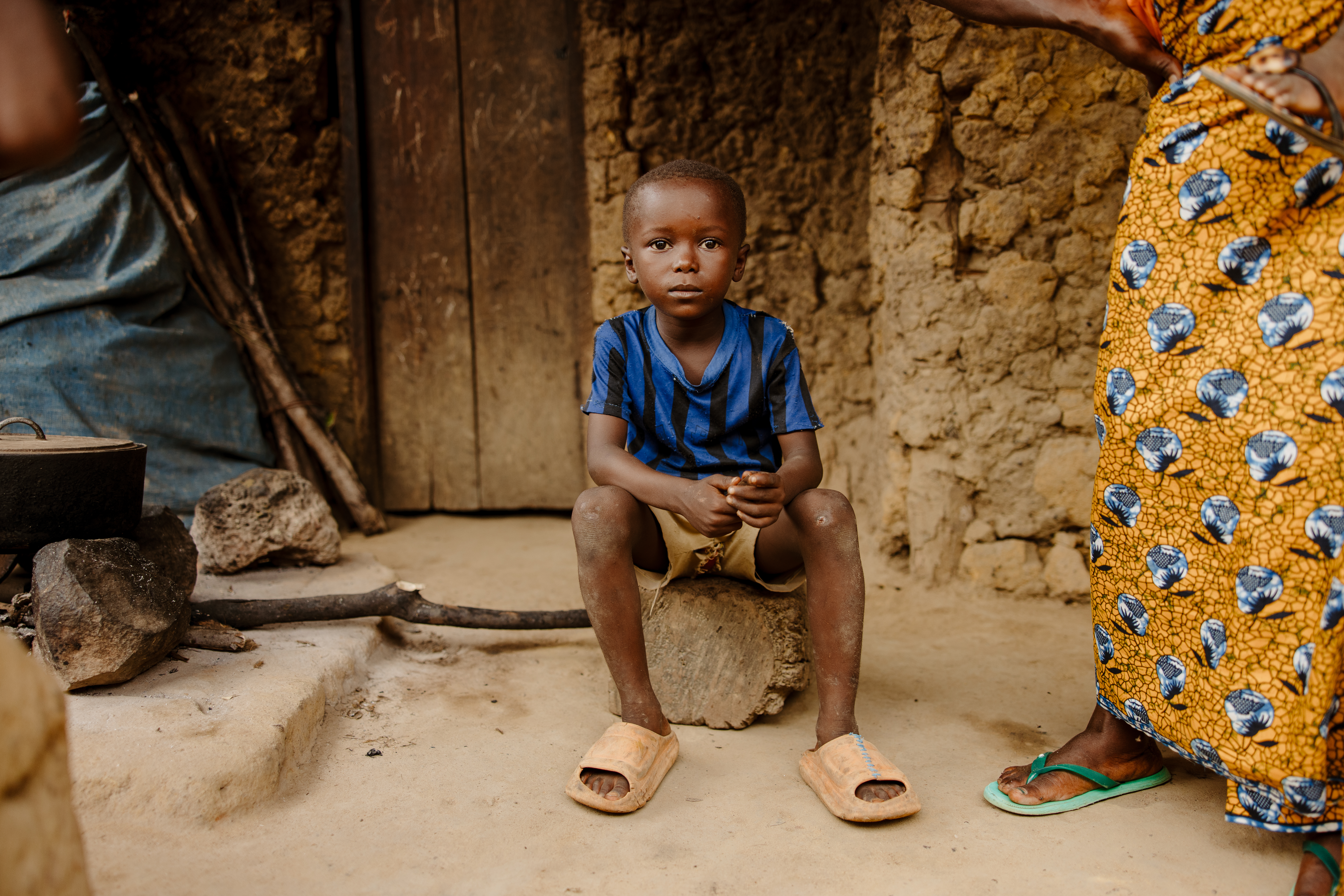 Young boy sat in front of his home in rural area of Sierra Leone