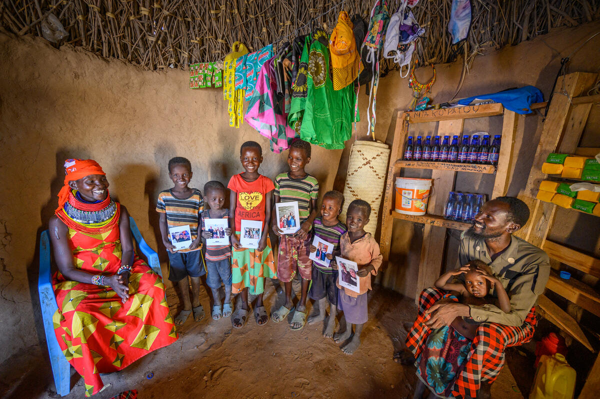 Family from Kenya in their home, six of their children are holding pictures of their Chosen Sponsors