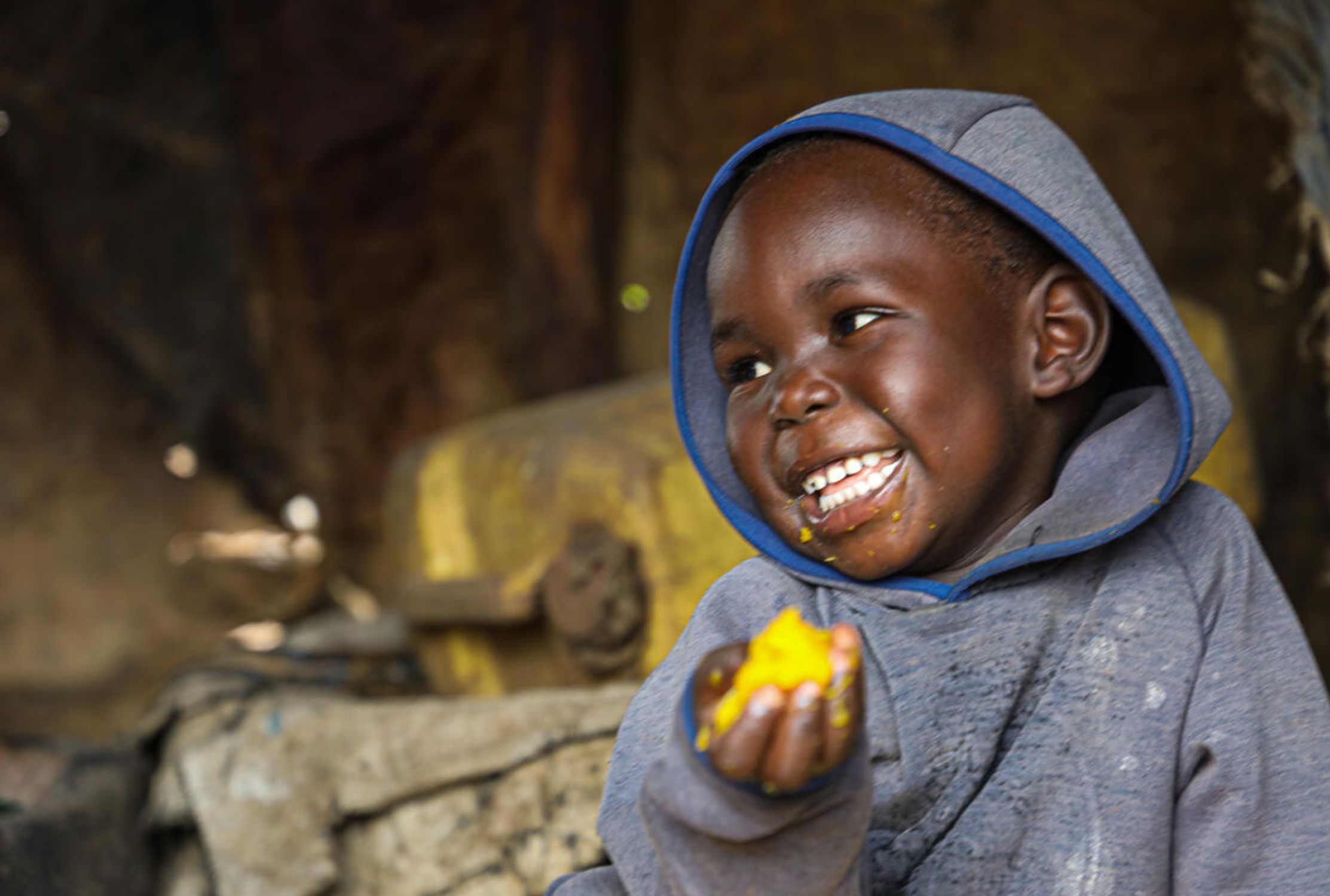 Ugandan refugee child smiling and eating food