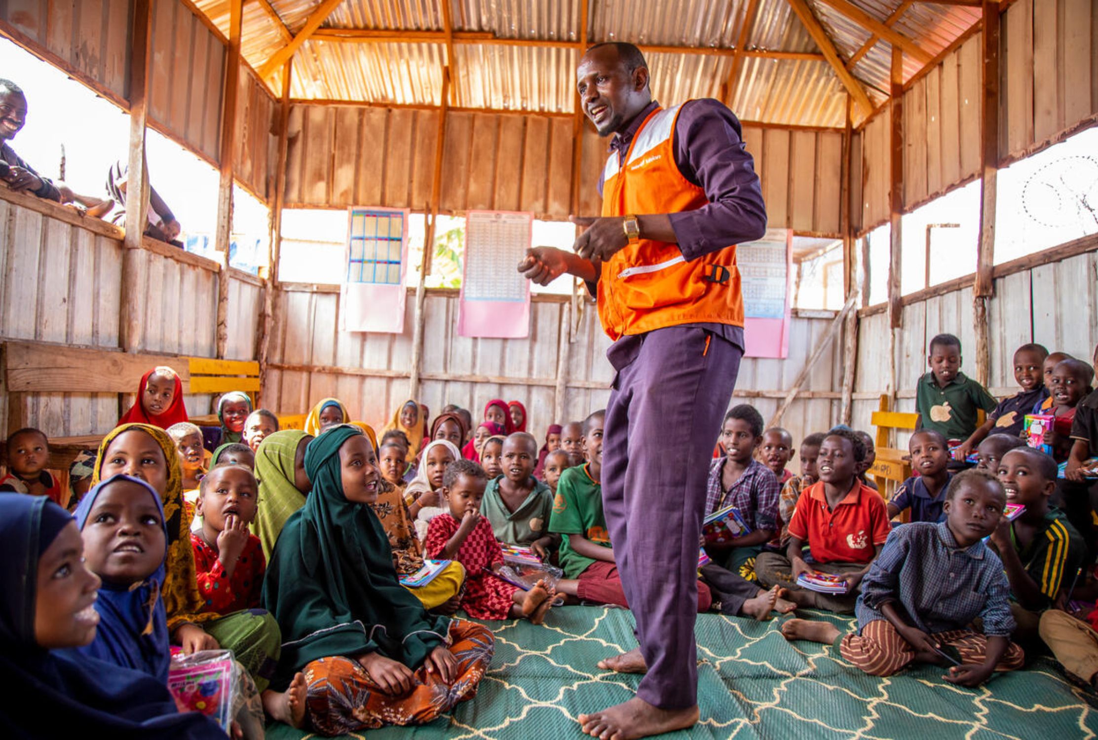World Vision staff member in Somalia standing and speaking to children sat on the floor
