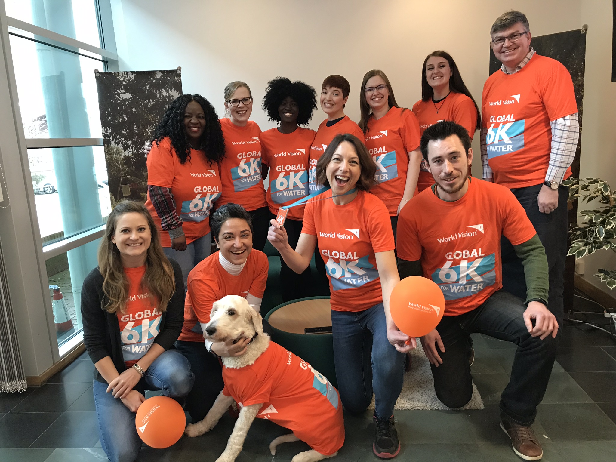 A group of World Vision staff members gathered wearing orange World Vision t-shirts