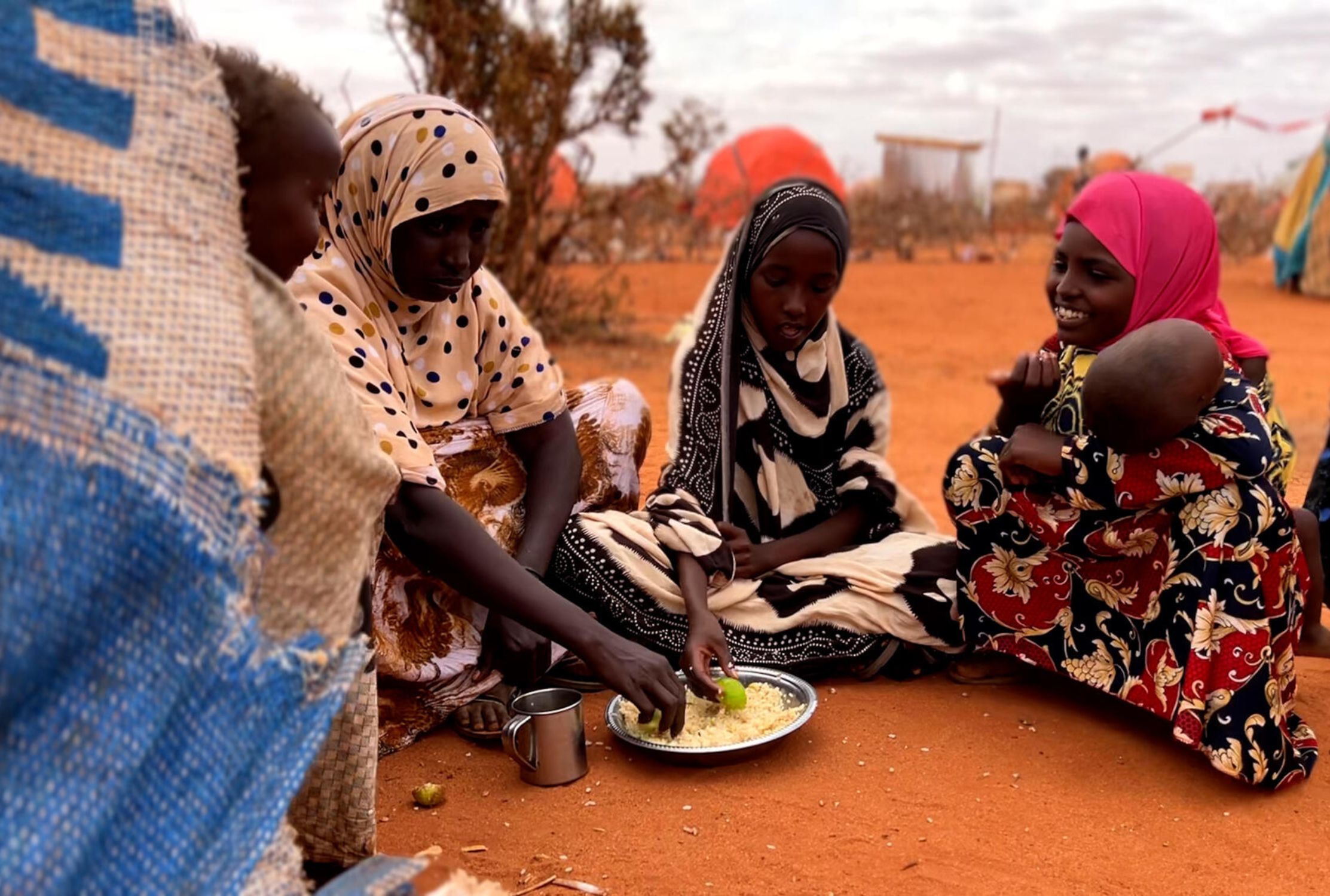 Somali grandmother, mother and daughter sat on the floor eating rice together