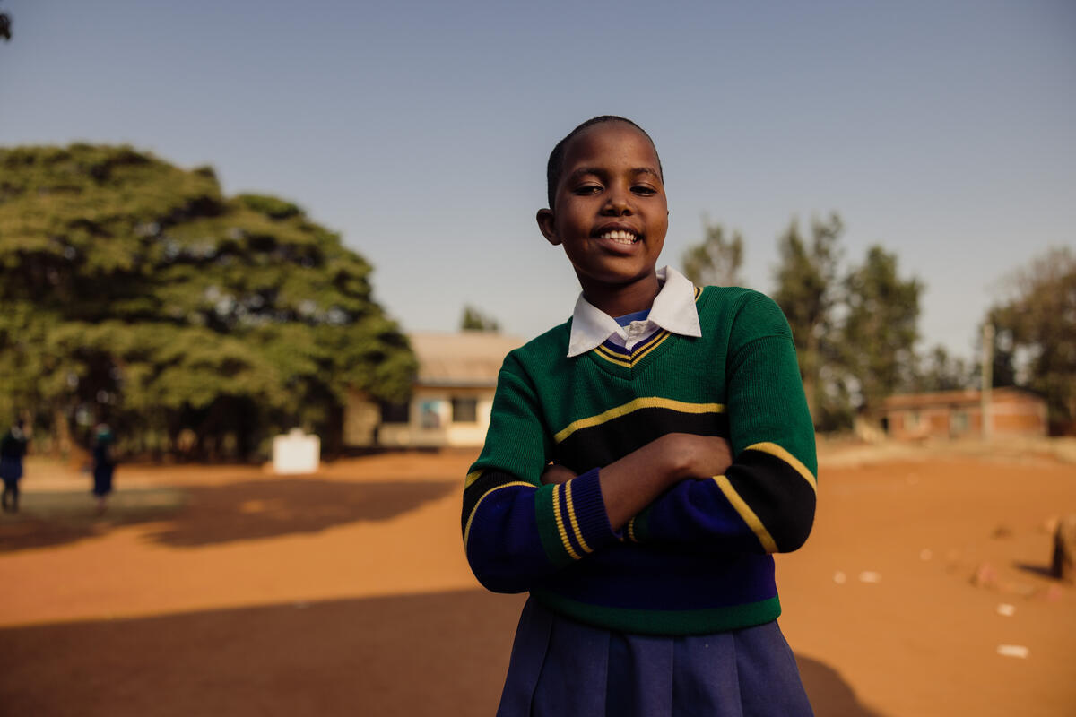 11-year-old Frida smiling outside of her school building in Tanzania